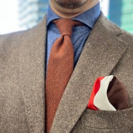 茶色のスーツ（ツイード素材）ｘインディゴのニットシャツｘオレンジ無地のウールタイ